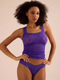 Woman wearing a purple lace lingerie set against a beige background