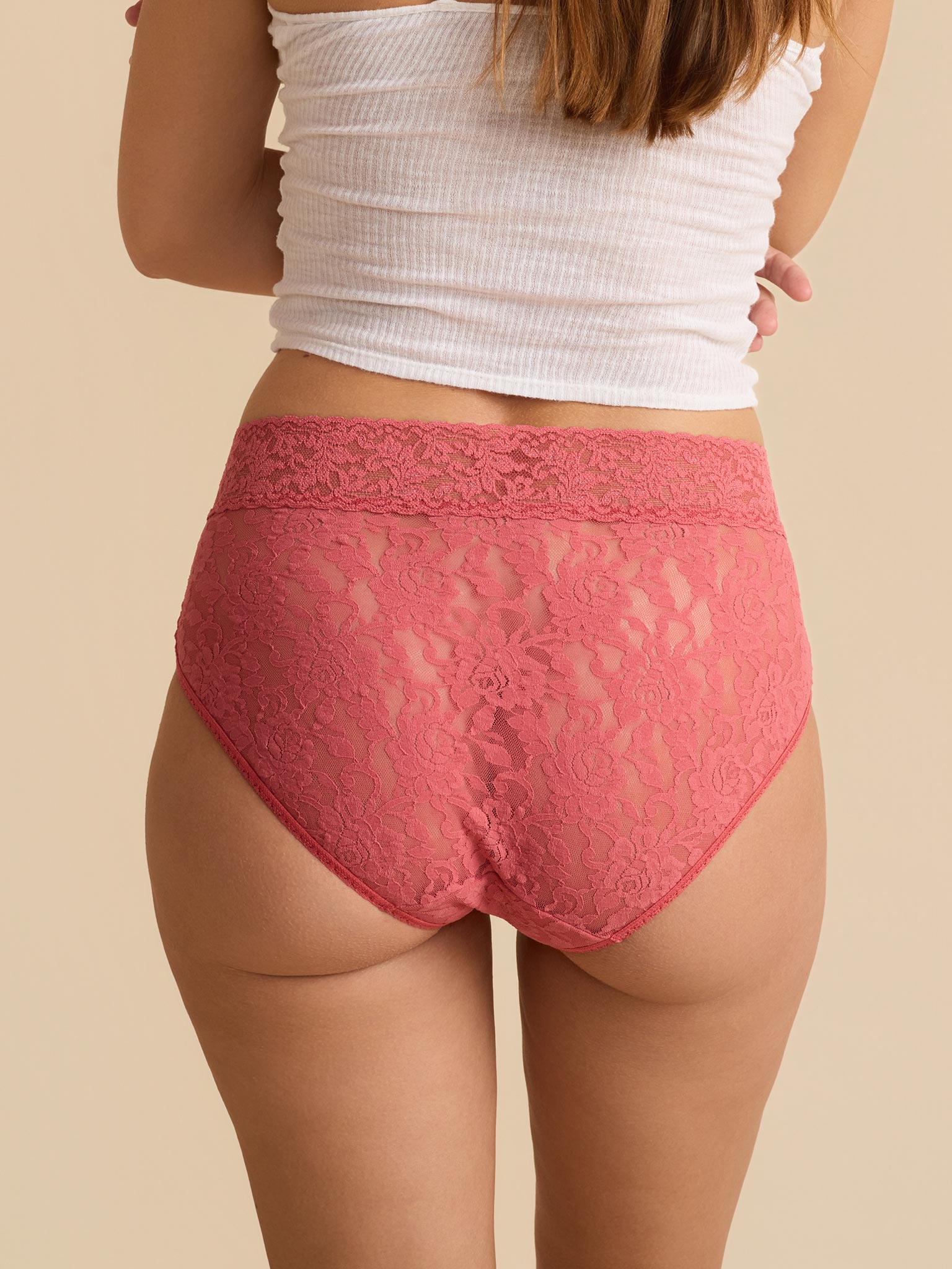 Person wearing red lace underwear on a beige background