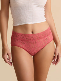 Person wearing red lace underwear and a white top on a beige background