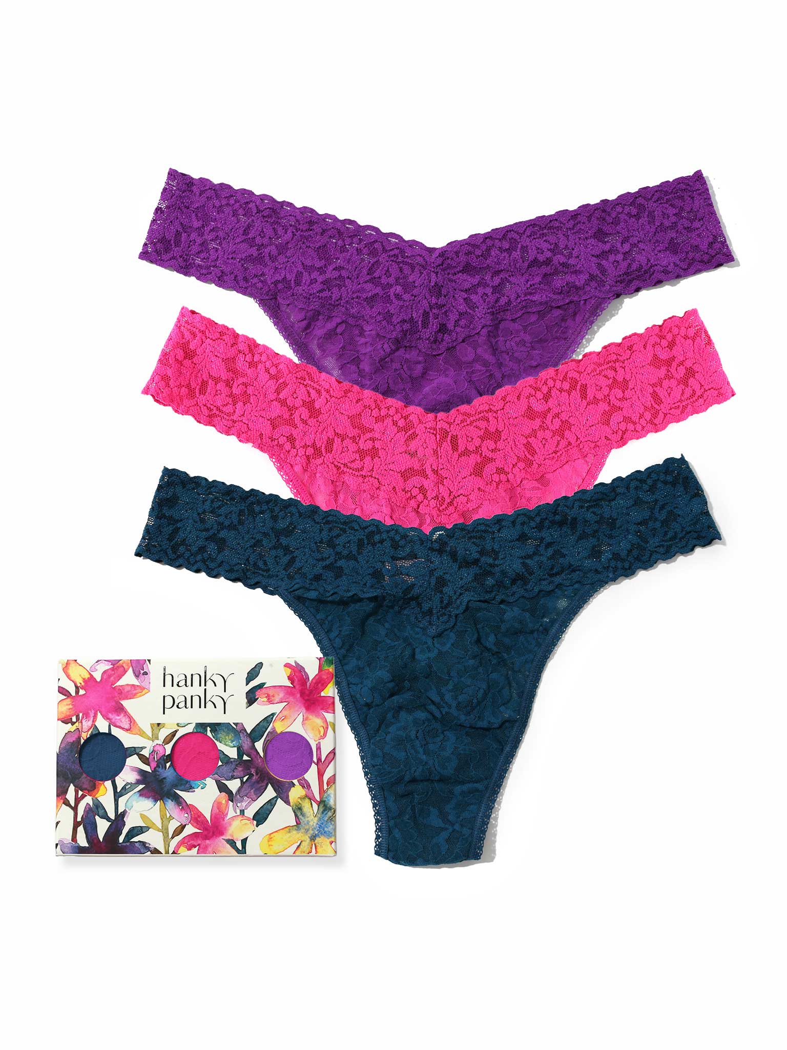 Three pairs of lace thongs in purple, pink, and blue with a floral packaging box on a white background.