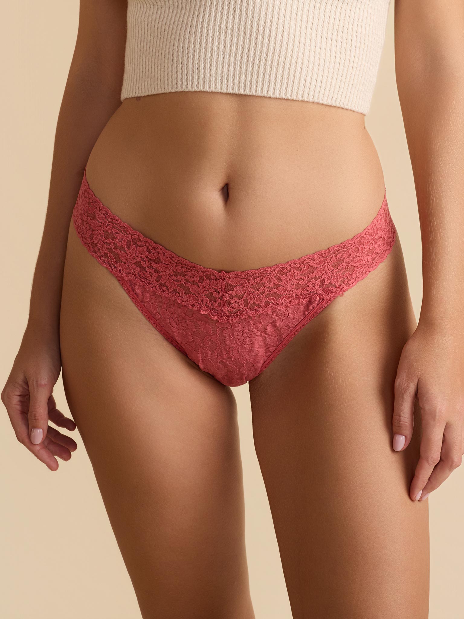 Red lace underwear worn by a person on a beige background