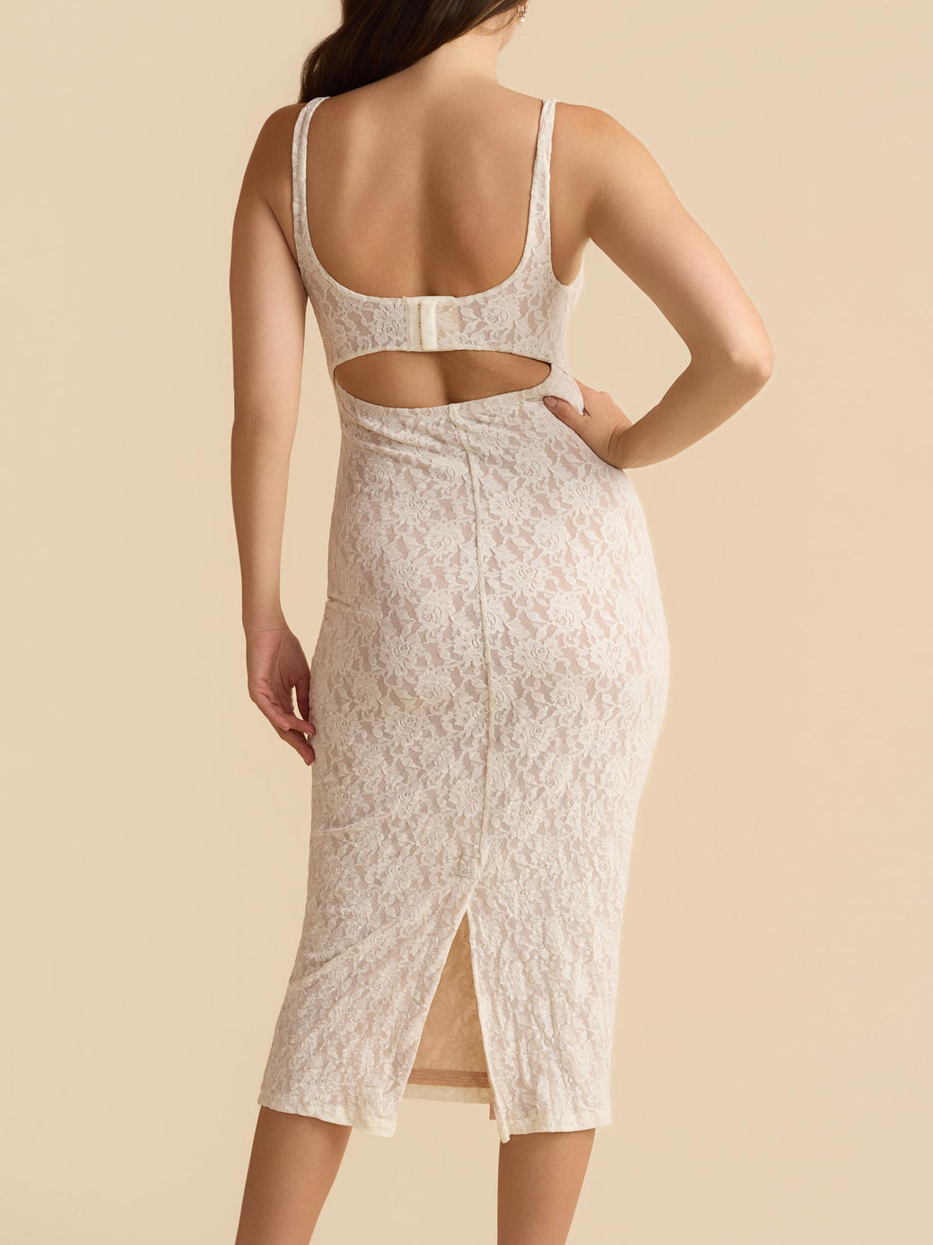 Woman wearing a white lace dress with cut-out design on a beige background