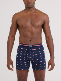 Man wearing navy boxer briefs with flag pattern and SAXX branding on a white background ready to support team USA with patterned USA signet monograms throughout