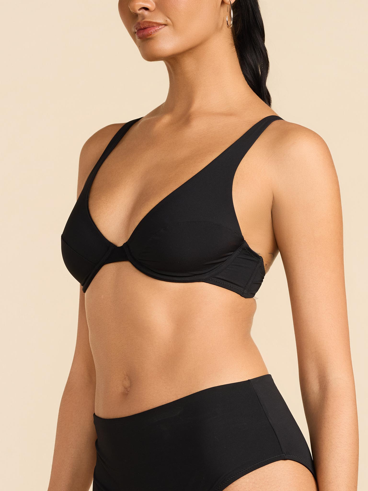 Woman wearing a black bikini against a beige background
