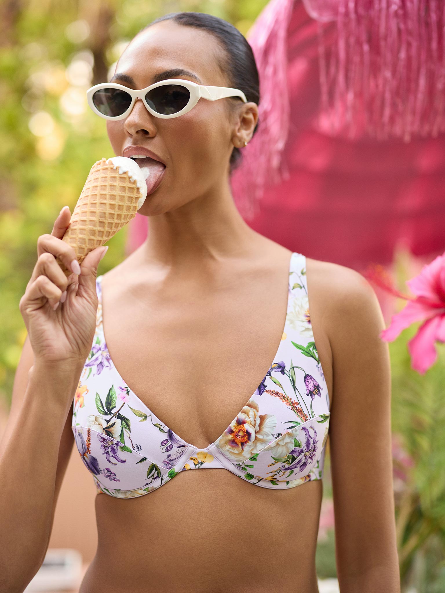 Woman in a floral bikini eating an ice cream cone with a colorful background