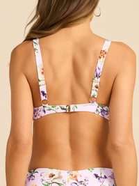 Floral bikini top worn by a person on a beige background