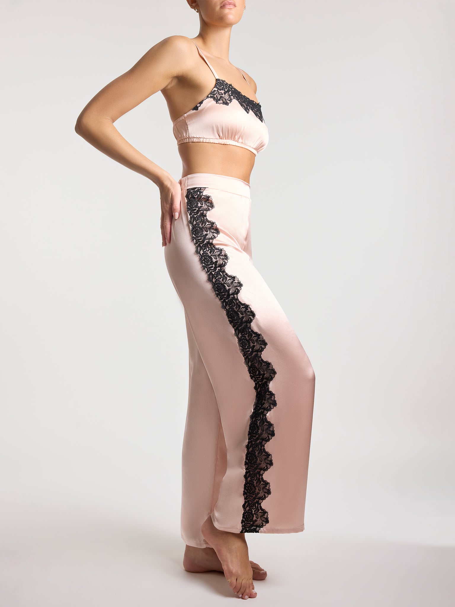 Woman wearing a pink lace top and pants on a white background