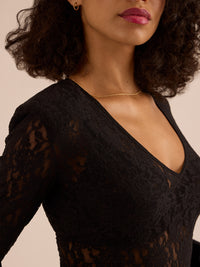 Woman wearing a black lace top with a plain background