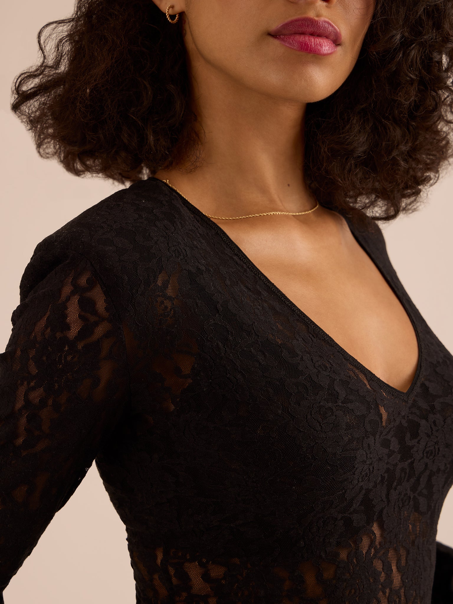 Woman wearing a black lace top with a plain background