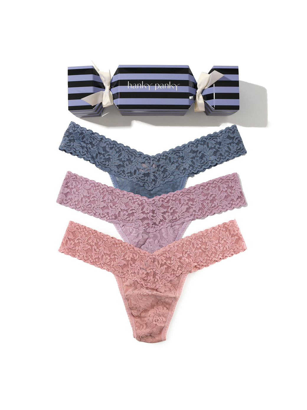 Set of three pairs of lace underwear in blue, pink, and red with a striped candy cracker on a white background.