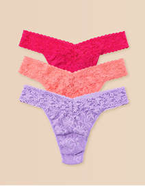 Three pairs of lace thongs in pink, red, and purple on a beige background