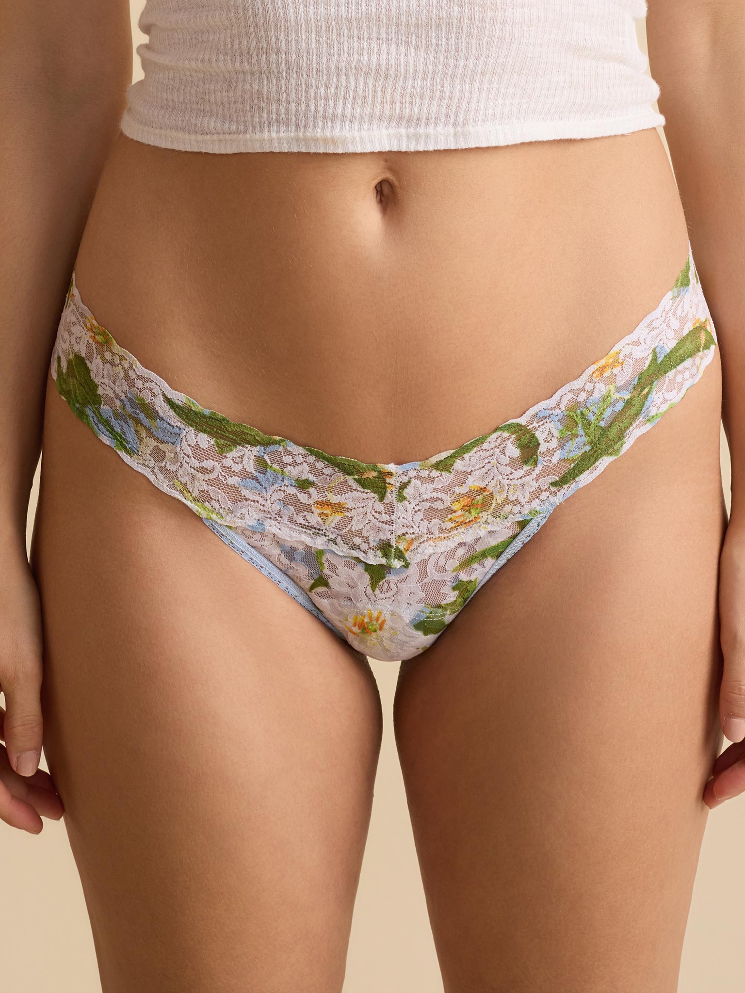 Floral lace underwear worn by a person on a beige background