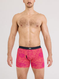 Man wearing pink floral boxer briefs with a black waistband on a white background