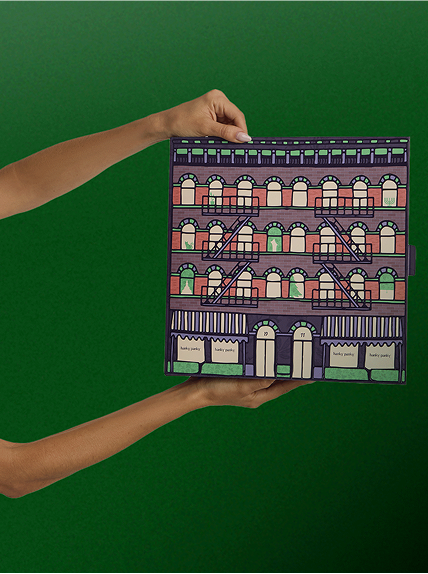 Hand holding a patterned book with a green background