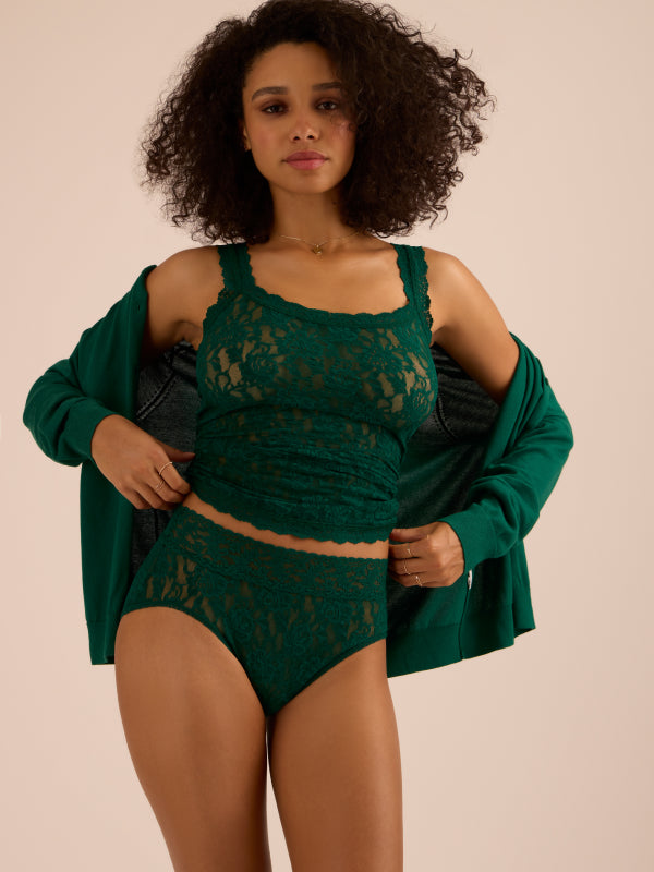 Woman wearing a green lace outfit with a matching cardigan on a beige background